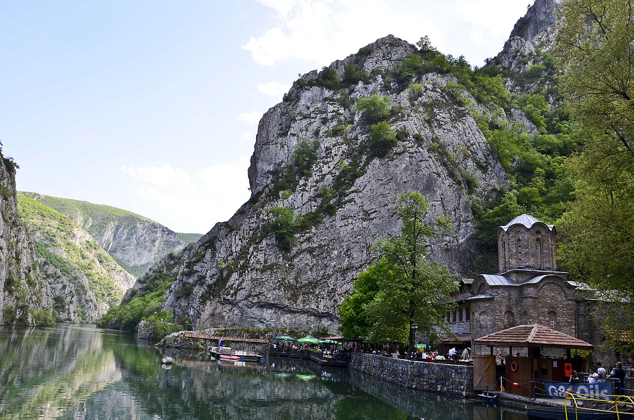 St. Andrew's Monastery below the cliffs of Matka Canyon, with boats on the lake