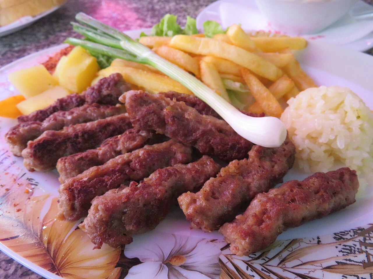 A plate of kebapi with fries, rice and spring onion in Skopje's Old Bazaar